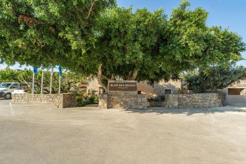 a large tree with a sign in a parking lot at Hotel Blue Sea Beach, Affiliated by Meliá in Stalís