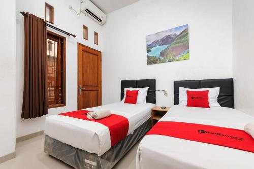 two beds in a room with red and white at RedDoorz @ Jalan Danau Limboto in Malang