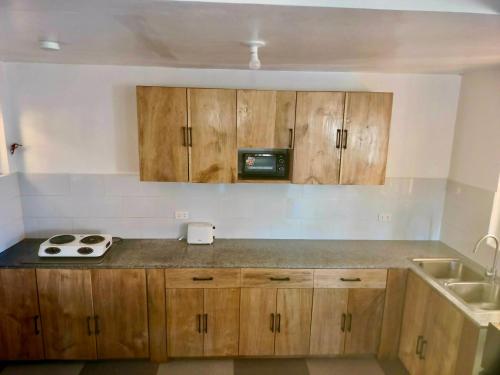 a kitchen with wooden cabinets and a sink at Noah Bed&Breakfast 3 Private Room NEWHOME Quiet Place to Stay 14 Minutes to PPS Airport in Puerto Princesa City
