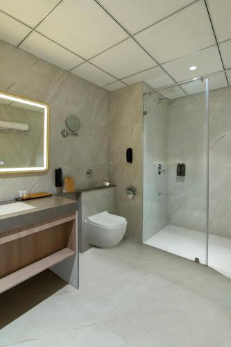 a bathroom with a shower and a toilet and a sink at Enrise By Sayaji Somnath in Somnath