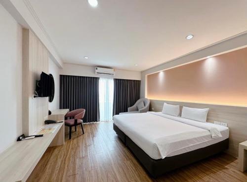a hotel room with a large bed and a chair at Miloft Sathorn Hotel in Bangkok