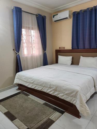 a bedroom with two beds and a window with blue curtains at Cogent Apartments and Hotel in Uyo