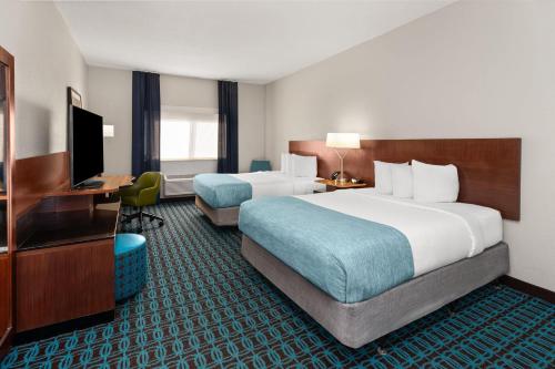 a hotel room with two beds and a television at Wingate by Wyndham Oshkosh in Oshkosh