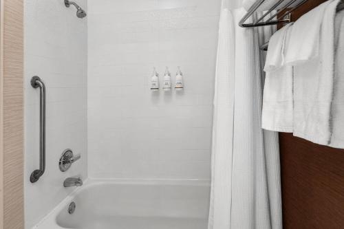 a bathroom with a white tub and a shower at Wingate by Wyndham Oshkosh in Oshkosh