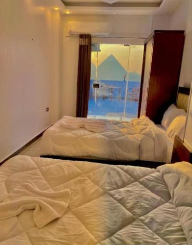 two beds in a bedroom with a view of the ocean at malak pyrameds rofe top in Cairo
