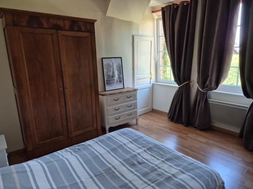 a bedroom with a bed and a dresser and windows at Gite Normandie in Forges-les-Eaux