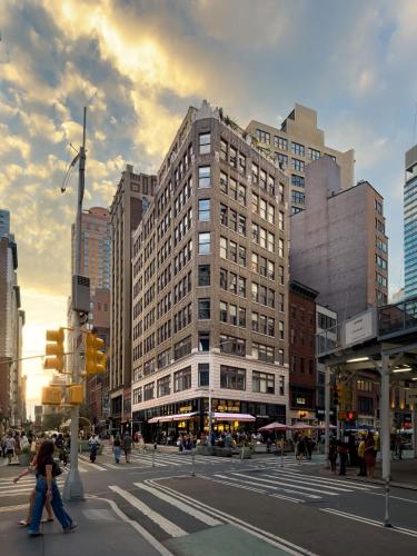 a city street with people crossing the street in front of a building at Madison Square Hotel Near NoMad in New York