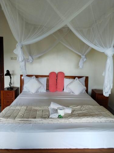 a bedroom with a bed with red pillows at Pondok Alam Bukit in Tirtagangga