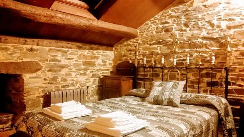 1 dormitorio con 1 cama en una pared de piedra en Apartamentos Rurales Vega de Llan, en Taramundi