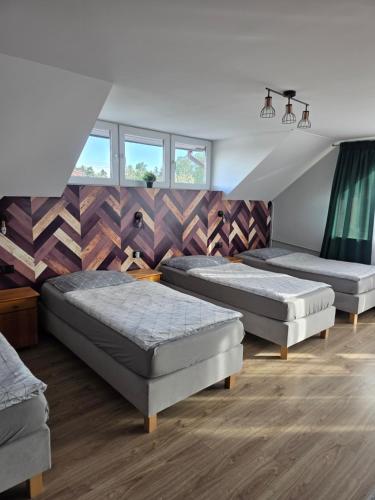 three beds in a room with wooden floors and windows at Pokoje Hotelowe Gościniec in Siedlce