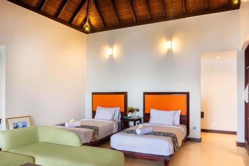 a hotel room with two beds and a chair at Chads Dive Resort Lembeh in Bitung