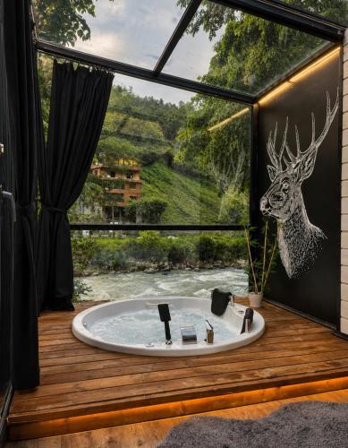 a bathroom with a tub with a deer on the window at MOLVA Bungalows Otel in Çamlıhemşin