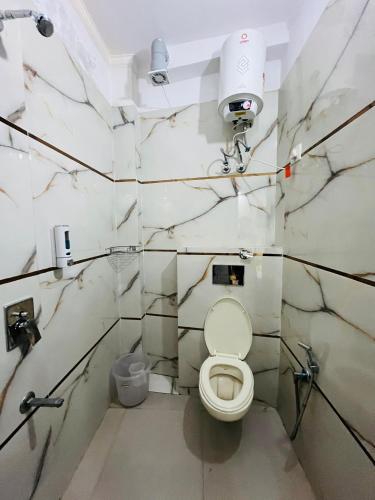 a white bathroom with a toilet and a camera at Hotel Prithvi Studio - RDC And Santosh Hospital in Ghaziabad