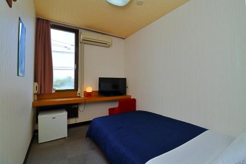 a bedroom with a bed and a desk and a window at Ribera Inn in Satsumasendai