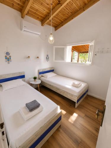 two beds in a white room with a window at Villa Keren in Oropos