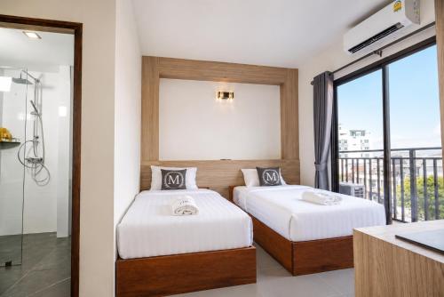 two beds in a room with a balcony at M&M Hotel in Vang Vieng