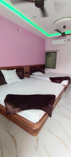 two beds in a room with green lights on the ceiling at Shri Goara palece in Godarpura