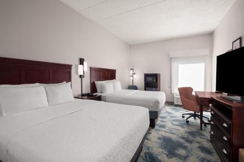 a hotel room with two beds and a desk and a television at Hampton Inn Winfield Teays Valley in Teays Valley Estates
