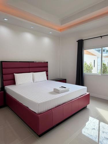 a bedroom with a large bed with a red headboard at โรงแรม นีโอ รีสอร์ท in Ban Thap Nang