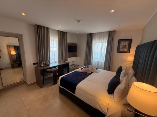 a hotel room with a bed and a desk and a room at Grand Harbour Hotel in Valletta