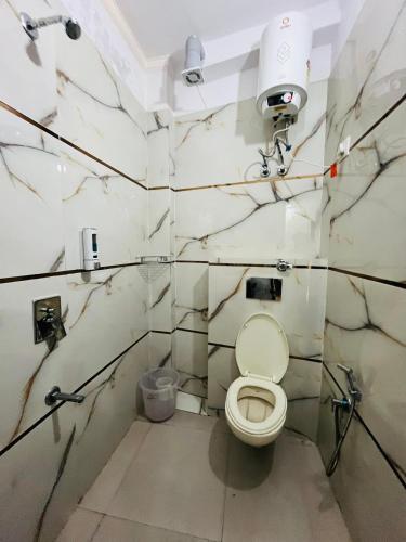 a bathroom with a toilet with marble walls at Hotel PP Tower - Near Ghaziabad Railway Station in Ghaziabad
