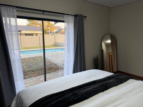 a bedroom with a large window with a view of a pool at Natures Nest with Mongi Hazyview in Hazyview