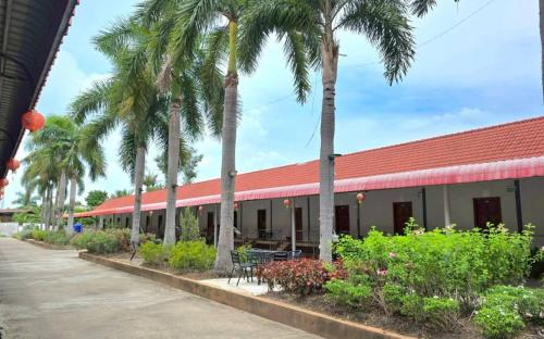 a building with palm trees and a red roof at ปราสาทรีสอร์ท in Prasat