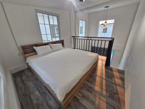 a bedroom with a bed with white sheets and two windows at River View Villas in Vang Vieng