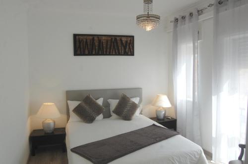 a white bedroom with a bed with two lamps at Suites Inn Lagos in Lagos