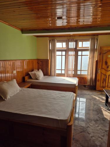 two beds in a room with two windows at Tilanjali Stay in Soreng