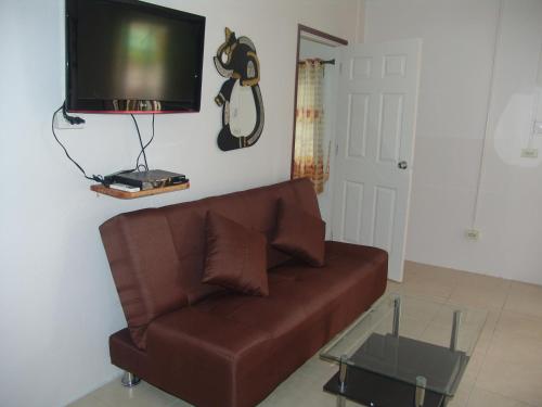 a living room with a brown couch and a flat screen tv at Ryans Resort in Prasat