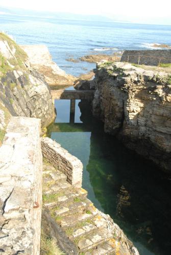 a stone bridge over a body of water near the ocean at Hotel Playa de las Catedrales in Reinante