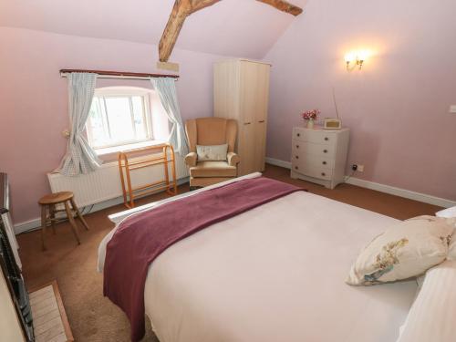 a bedroom with a bed and a chair and a window at Ewe Cottage in Ripon