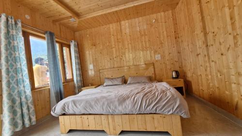 a bedroom with a bed in a wooden room at Daisy Divine in Harsil