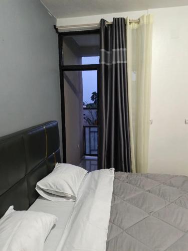 a bedroom with a bed and a window with a curtain at Mtg Apartment in Rubavu