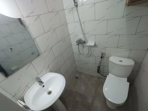 a white bathroom with a toilet and a sink at Mtg Apartment in Rubavu