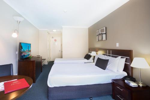 a hotel room with two beds and a desk at Riverside Hotel Southbank in Brisbane