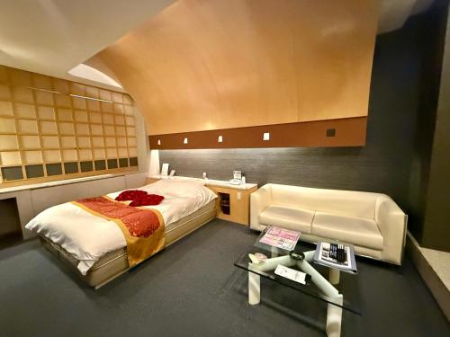 a bedroom with a bed and a desk and a couch at Hotel Shuyukan (Adult Only) in Izumi-Sano
