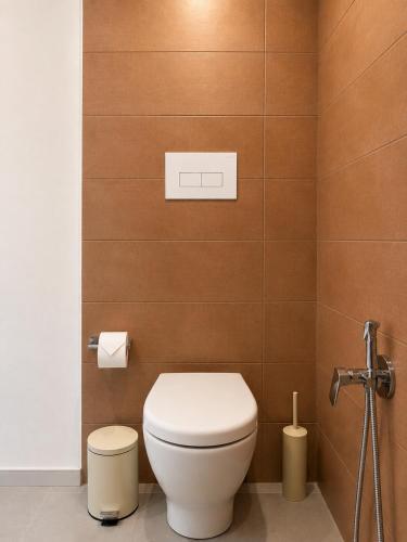 a bathroom with a white toilet and brown tiles at Liolà Rooms in Terrasini