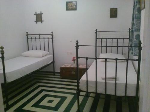 two beds in a room with green and white carpet at Captain Bay's Unique Heritage Home in Finikas