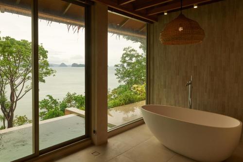 a bath tub in a bathroom with a large window at Amber Yao Noi in Ko Yao Noi