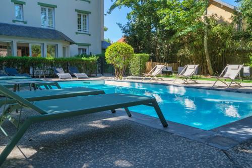 a pool with lounge chairs and a table next to a house at Hôtel Villa Flornoy Pornichet Baie de la Baule in Pornichet