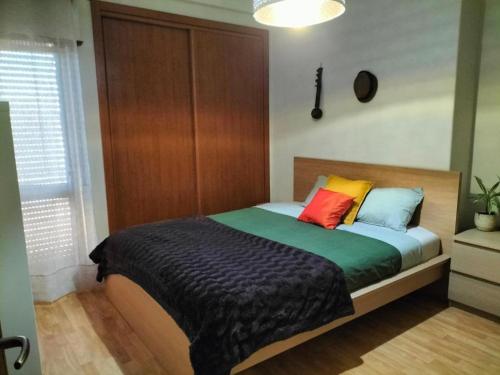 a bedroom with a bed with colorful pillows on it at Oeiras Central, near Beach & Public Transport in Oeiras