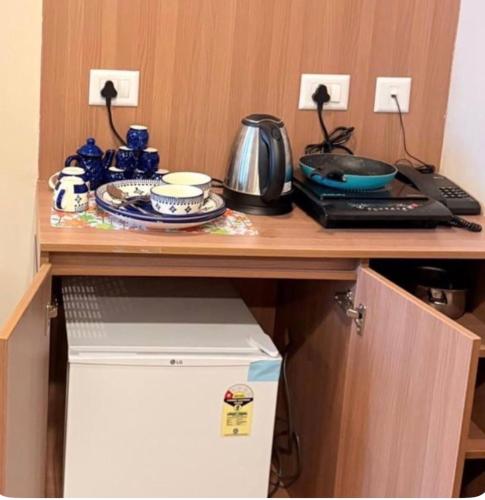 a cabinet with a desk with a table with dishes on it at Max Stays in Greater Noida