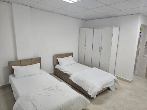 two beds in a room with white walls at غرف شباب عوقد in Salalah