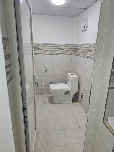 a white bathroom with a toilet and a shower at غرف شباب عوقد in Salalah