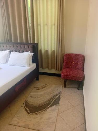 a bedroom with a bed and a red chair at Ponte Vedra Lodge in Mwanza