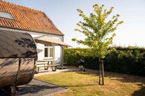 a house with a table and a tree in the yard at 't Boshuisje in Poperinge