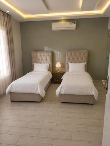a bedroom with two beds and a lamp on a tiled floor at منتجع الفيا - مسابح in Abha