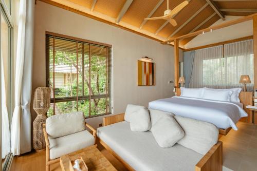 a bedroom with a large bed and a chair at Amber Yao Noi in Ko Yao Noi